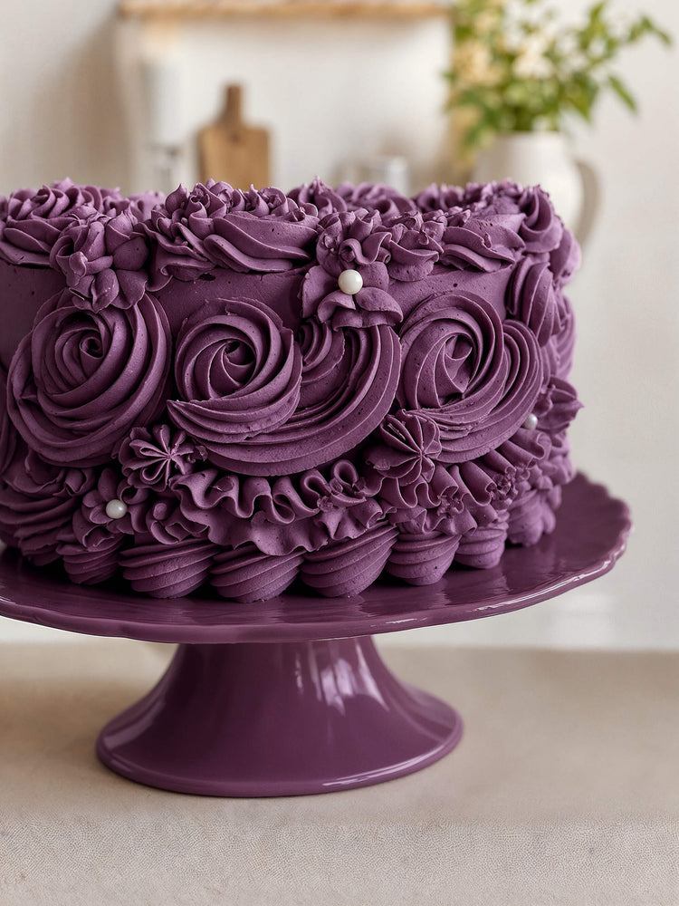 Torte mit lila Buttercreme-Rosetten auf einer Tortenplatte, gefärbt mit ölbasierter Lebensmittelfarbe