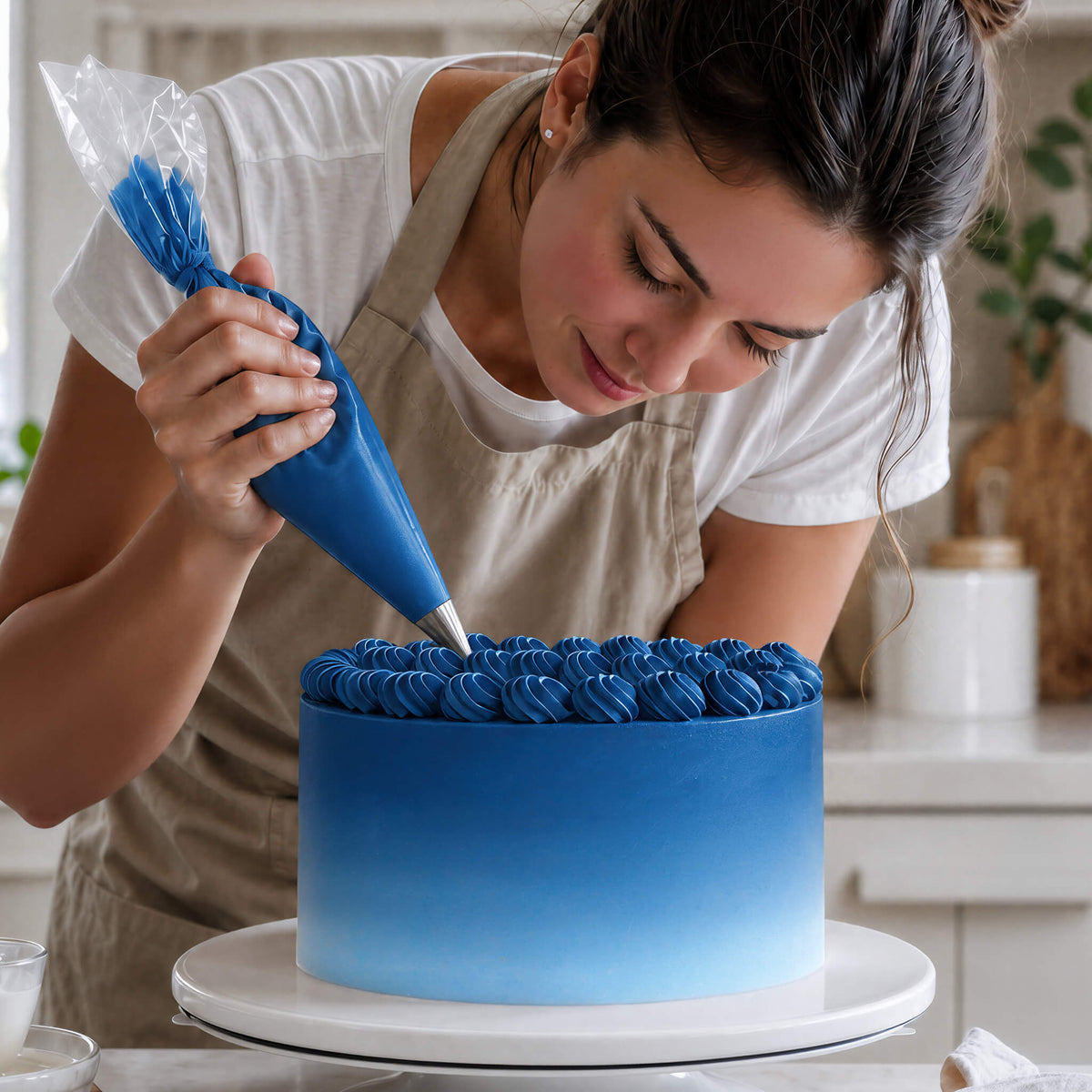 Frau spritzt Buttercreme-Tupfen in Blau auf eine Torte mit Farbverlauf von Blau zu Weiß