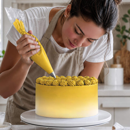 Frau spritzt Buttercreme-Tupfen in Gelb auf eine Torte mit Farbverlauf von Gelb zu Weiß