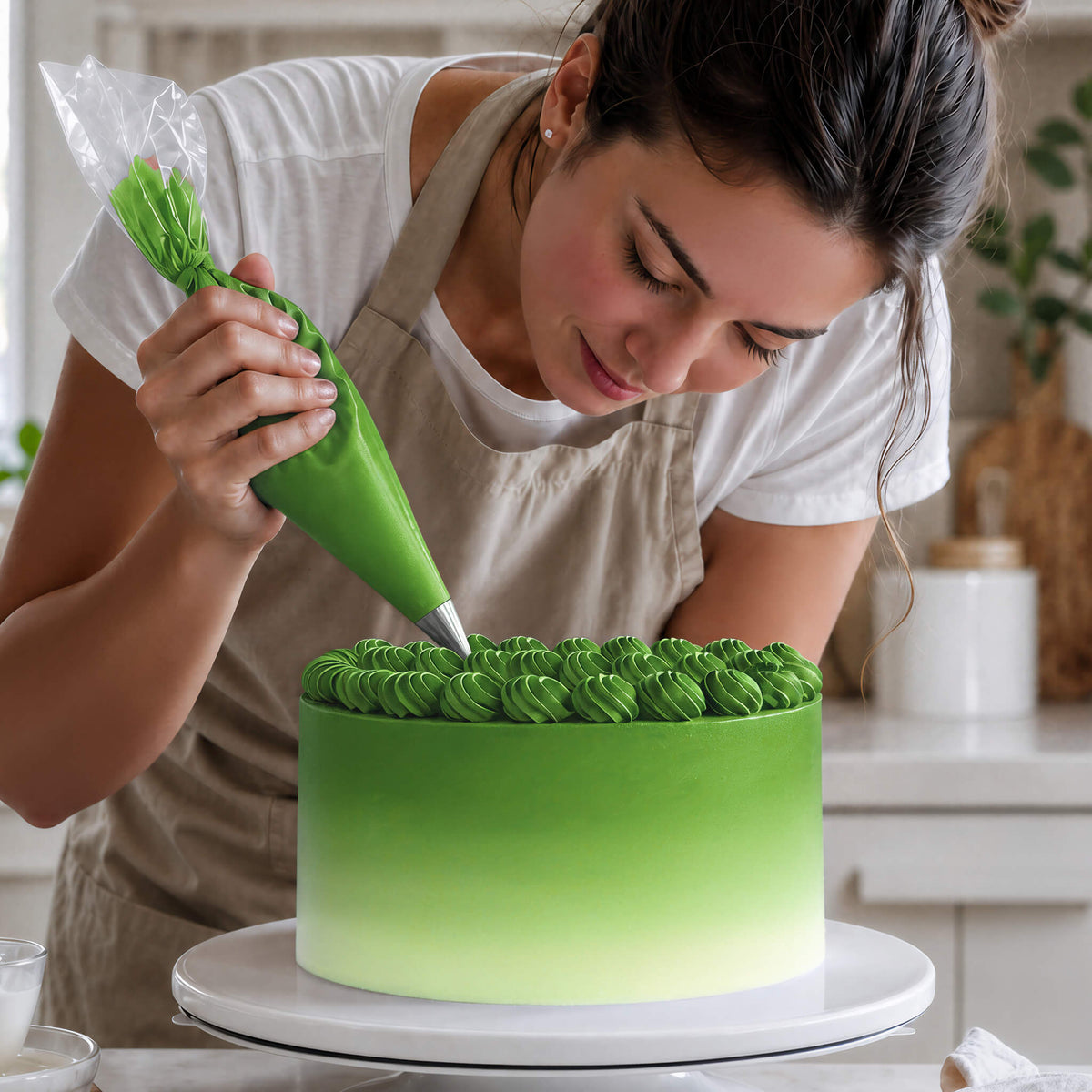 Frau spritzt Buttercreme-Tupfen in Grün auf eine Torte mit Farbverlauf von Grün zu Weiß
