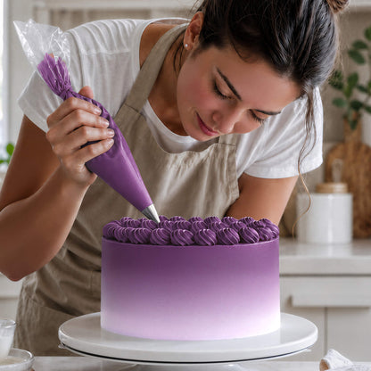 Frau spritzt Buttercreme-Tupfen in Lila auf eine Torte mit Farbverlauf von Lila zu Weiß