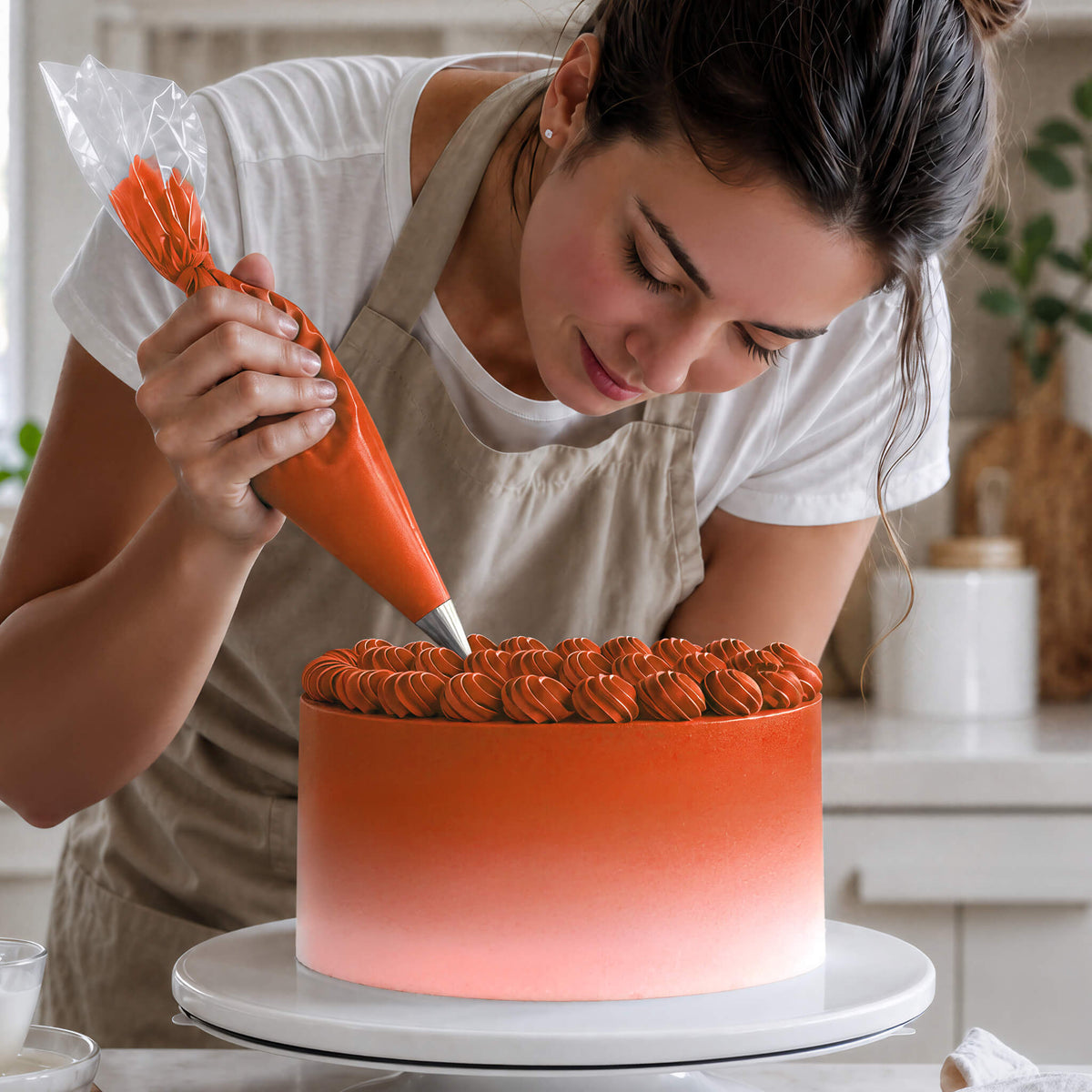 Frau spritzt Buttercreme-Tupfen in Orange auf eine Torte mit Farbverlauf von Orange zu Weiß