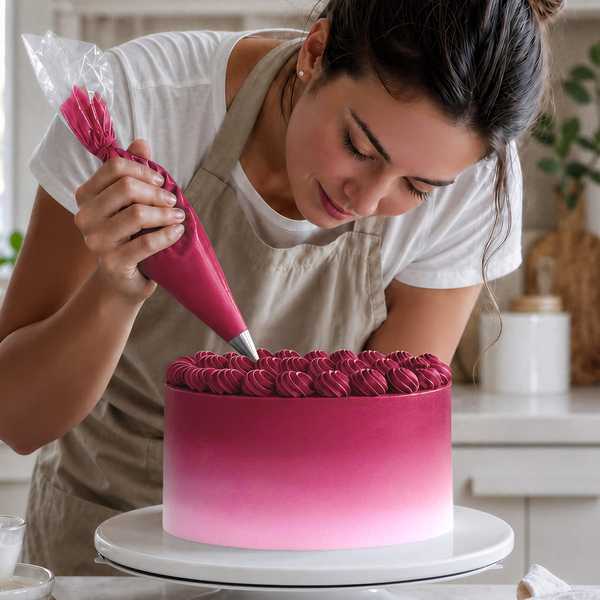 Frau spritzt Buttercreme-Tupfen in Pink auf eine Torte mit Farbverlauf von Pink zu Weiß