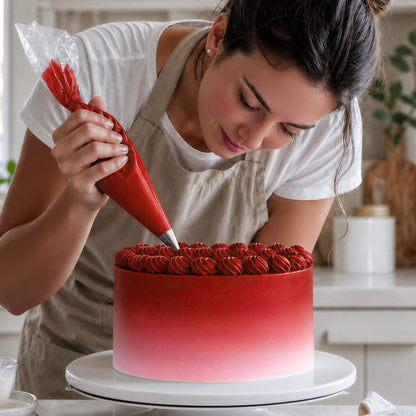 Frau spritzt Buttercreme-Tupfen in Rot auf eine Torte mit Farbverlauf von Rot zu Weiß