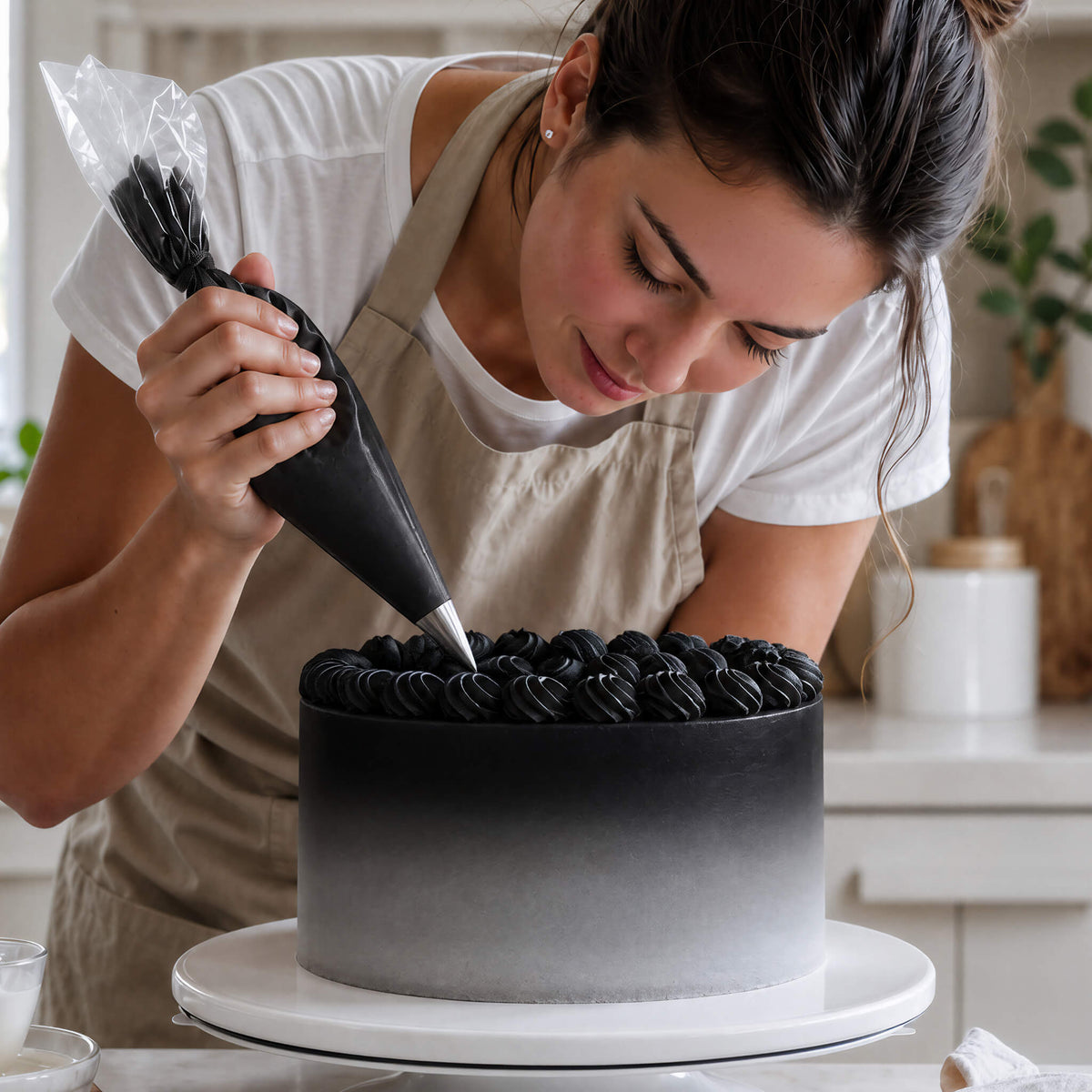 Frau spritzt Buttercreme-Tupfen in Schwarz auf eine Torte mit Farbverlauf von Schwarz zu Weiß